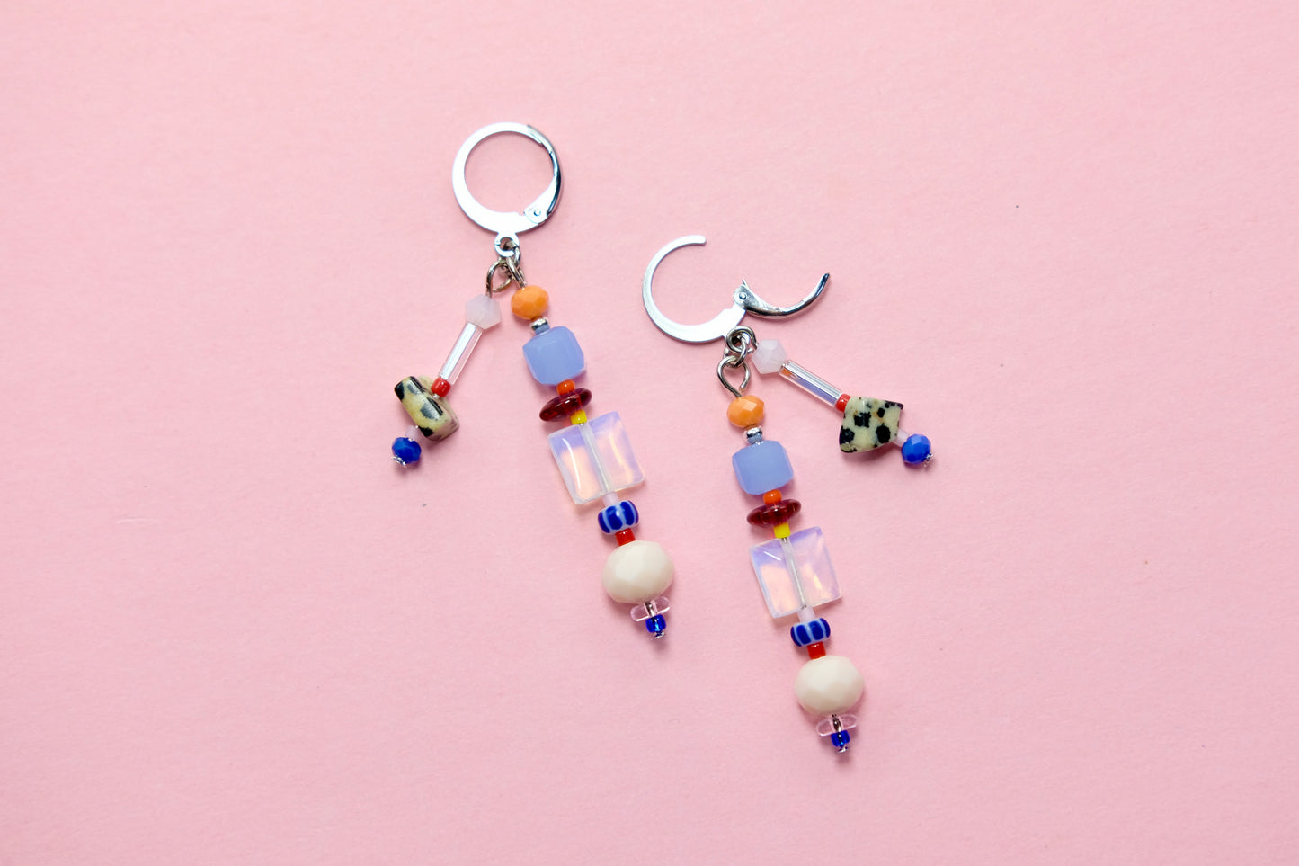 Colorful beaded earrings on a pink background