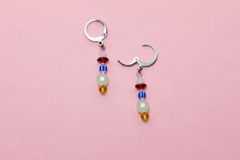 Pair of earrings with beads on a pink background