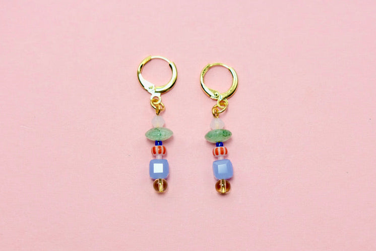 Pair of gold earrings with colorful beads on a pink background