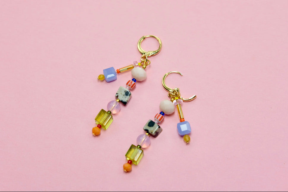 Colorful beaded earrings on a pink background
