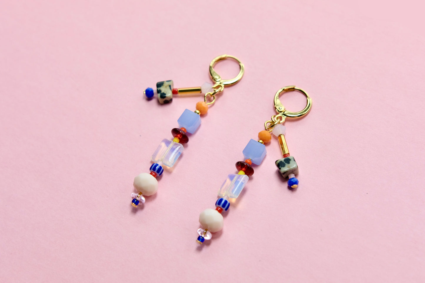 Colorful beaded earrings on a pink background