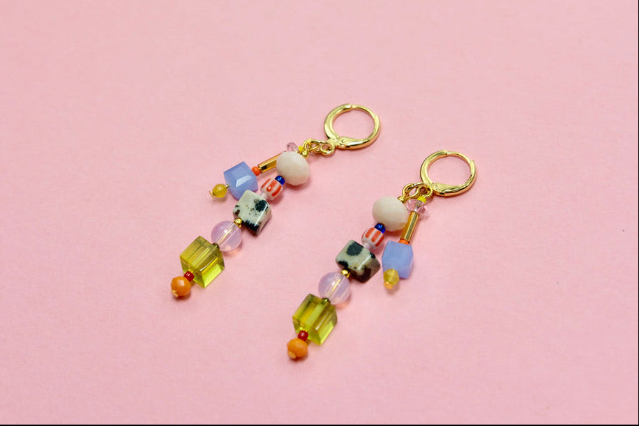 Colorful beaded earrings on a pink background