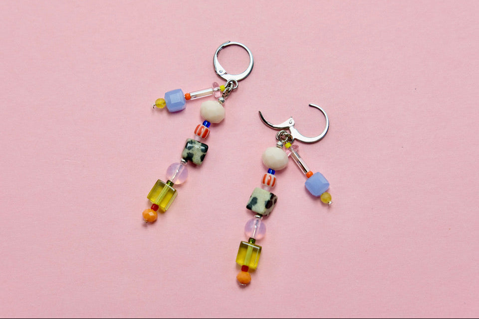 Colorful beaded earrings on a pink background