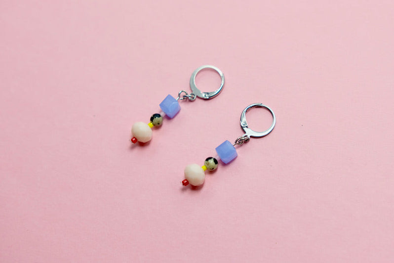 Pair of colorful beaded earrings on a pink surface