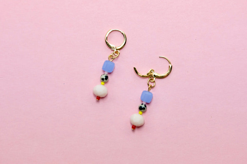 Pair of earrings with colorful beads on a pink background