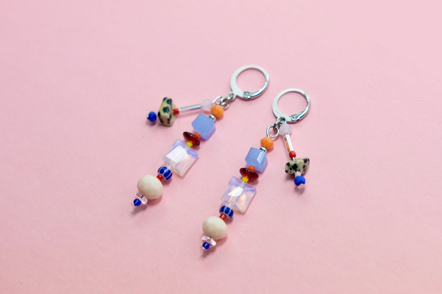 Colorful beaded earrings on a pink surface