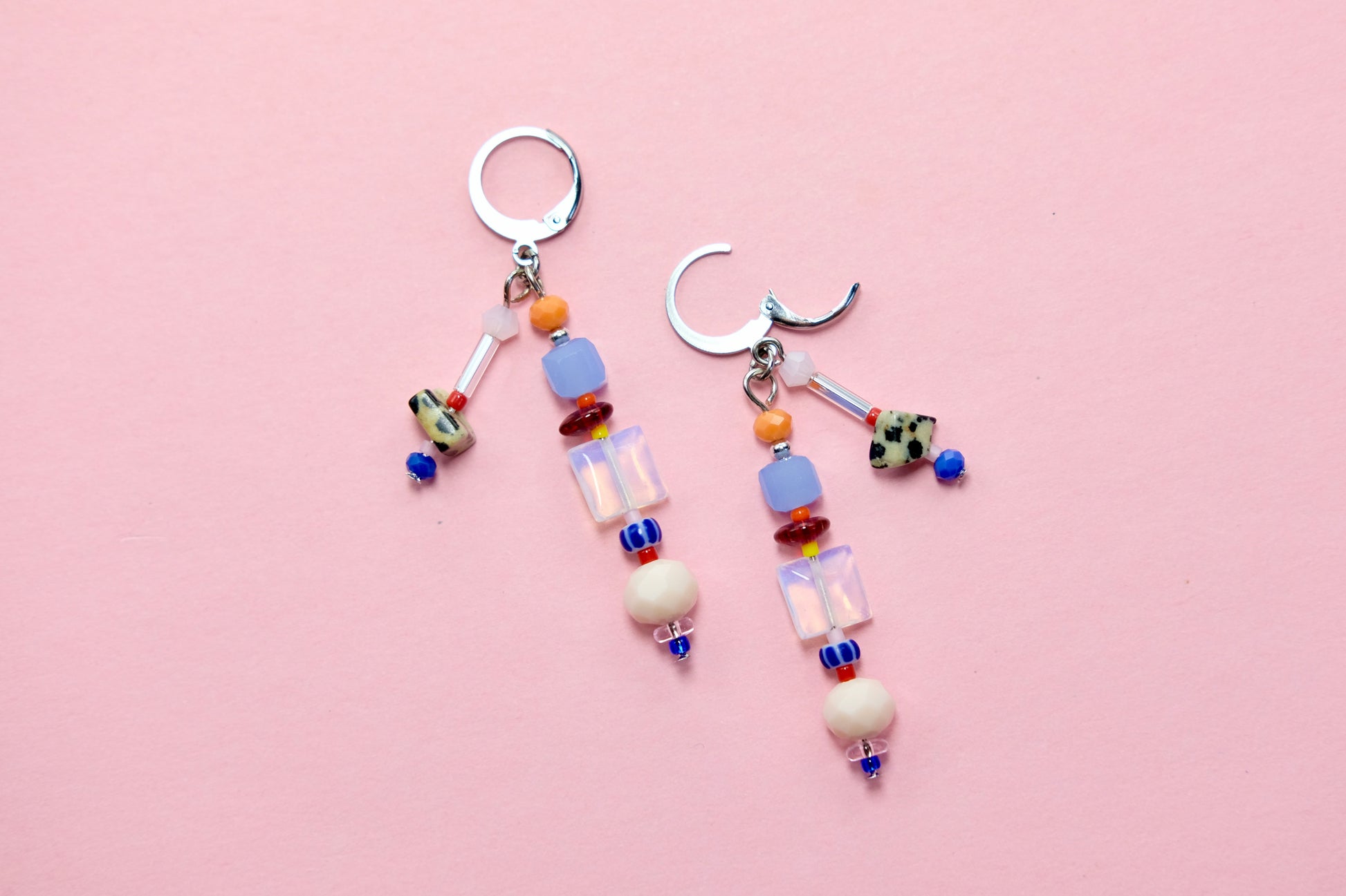 Colorful beaded earrings on a pink background