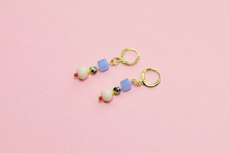 Pair of earrings with colorful beads on a pink background