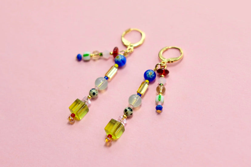 Colorful beaded earrings on a pink background