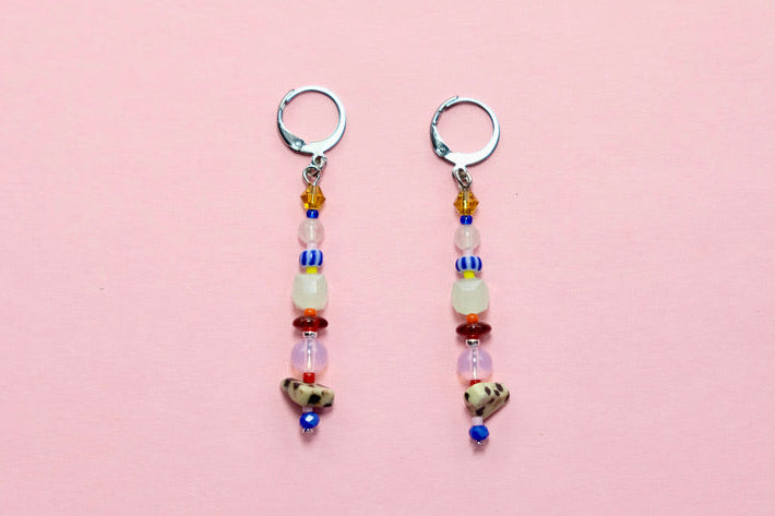 Pair of beaded earrings on a pink surface