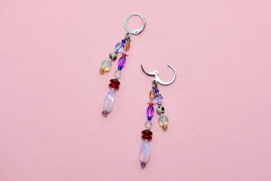 Colorful beaded earrings on a pink background