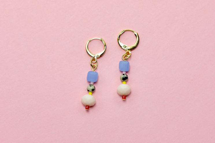 Pair of earrings with colorful beads on a pink background