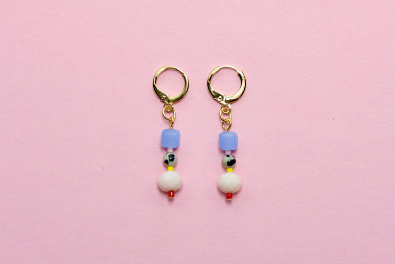 Pair of earrings with colorful beads on a pink background