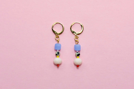 Pair of earrings with colorful beads on a pink background