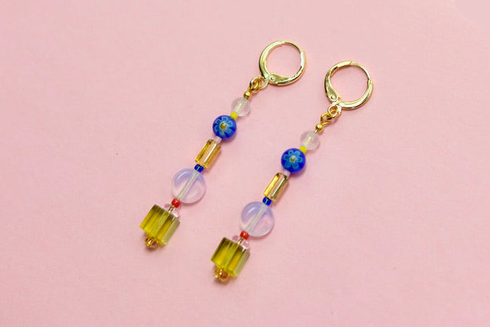 Pair of beaded earrings on a pink 