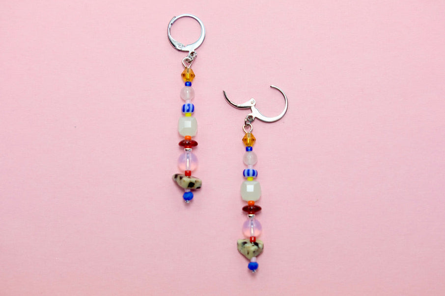 Two beaded earrings on a pink background
