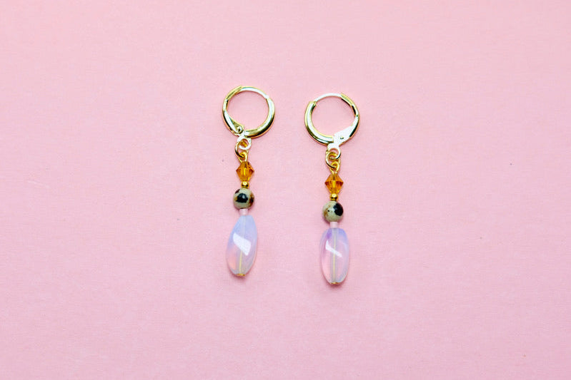 Pair of earrings with gemstones on a pink background