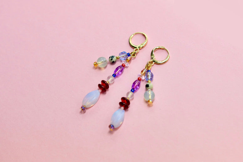 Colorful beaded earrings on a pink background