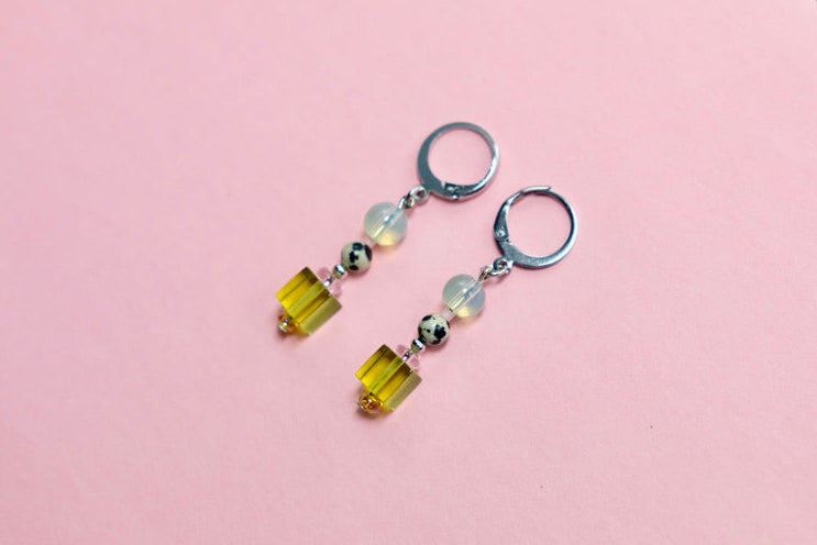 Pair of earrings with green beads on a pink background