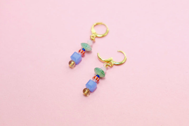 Pair of colorful beaded earrings on a pink background