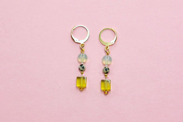 Pair of earrings with green beads on a pink background