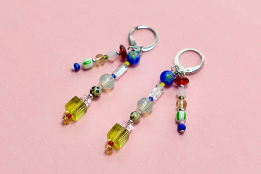 Colorful beaded earrings on a pink and textured surface