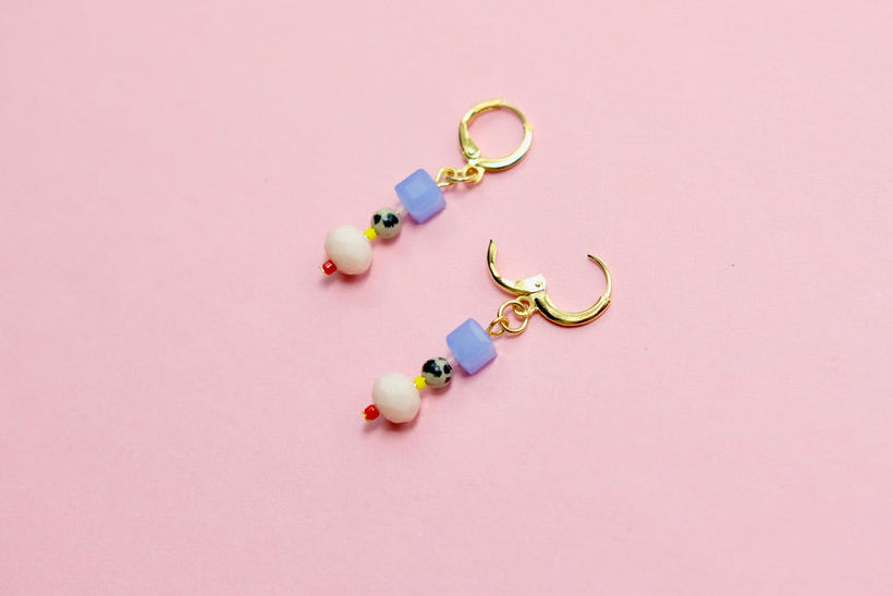 Pair of colorful beaded earrings on a pink background