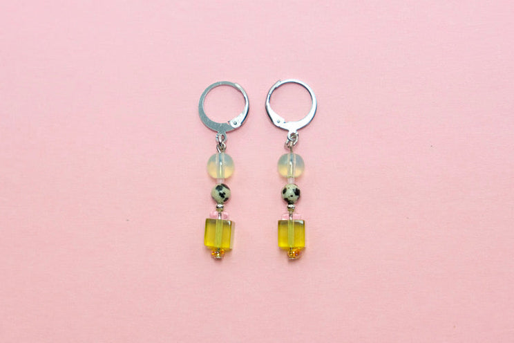 Pair of earrings with yellow beads on a pink background
