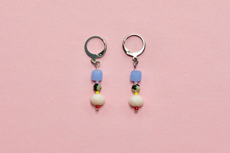 Pair of beaded earrings on a pink surface