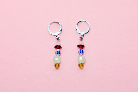 Pair of earrings with colorful beads on a pink background