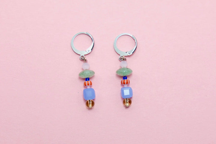 Pair of earrings with colorful beads on a pink background