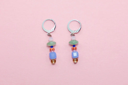 Pair of earrings with colorful beads on a pink background