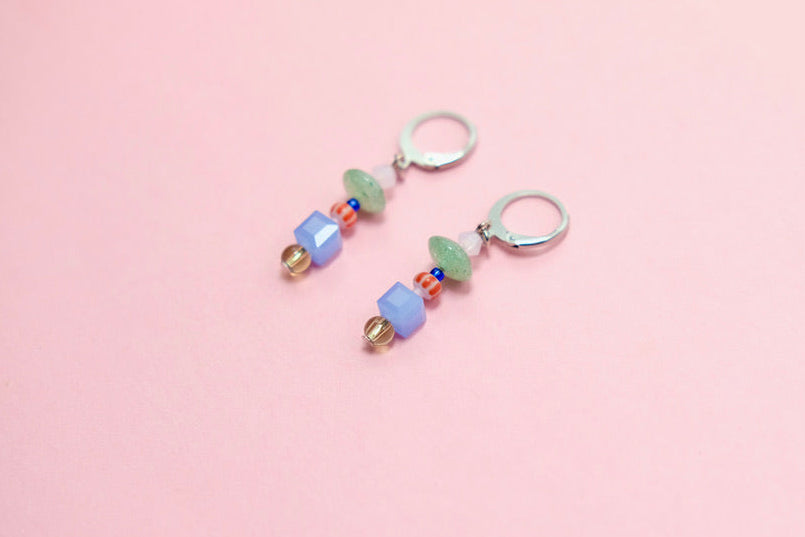 Pair of beaded earrings on a pink surface