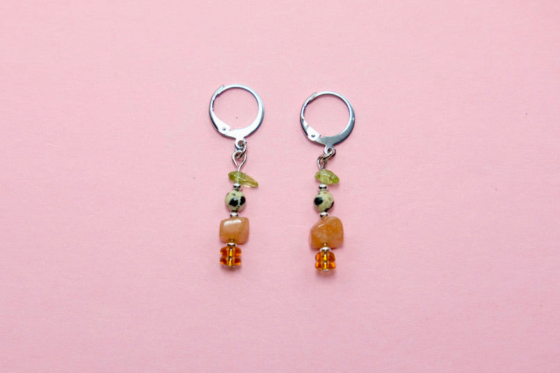 Pair of earrings with gem beads on a pink background