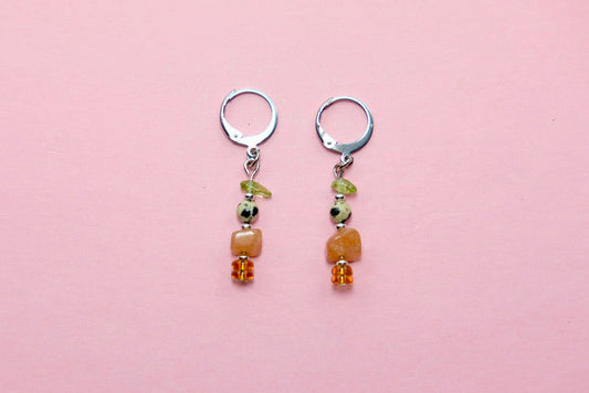Pair of earrings with gem beads on a pink background